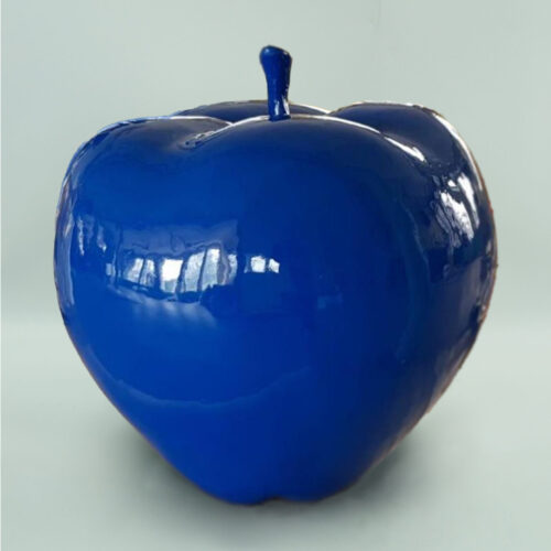 Błyszczące, intensywnie niebieskie jabłko ceramiczne na jasnym tle