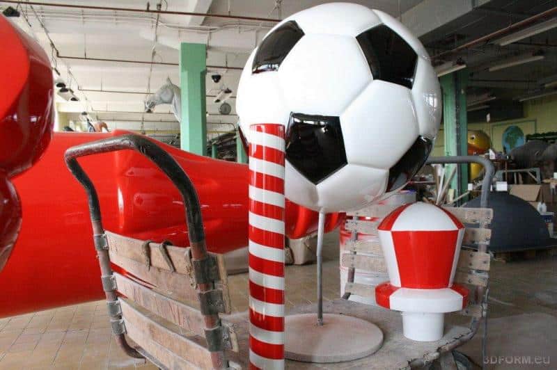 Coca-Cola-Flasche für die Euro 2012 1 Duże ozdobne elementy w kształcie piłki nożnej oraz czerwono-białego słupa wewnątrz warsztatu.