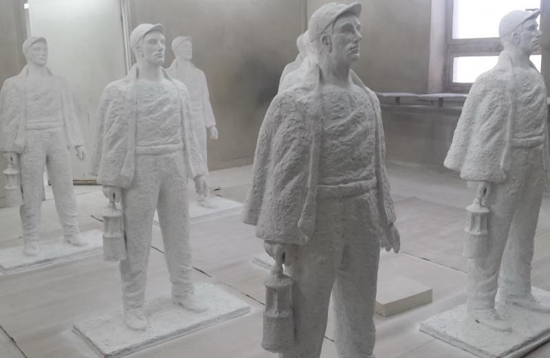 Bergarbeiterskulpturen 4 Posągi górników trzymających lampy górnicze ustawione w pomieszczeniu.