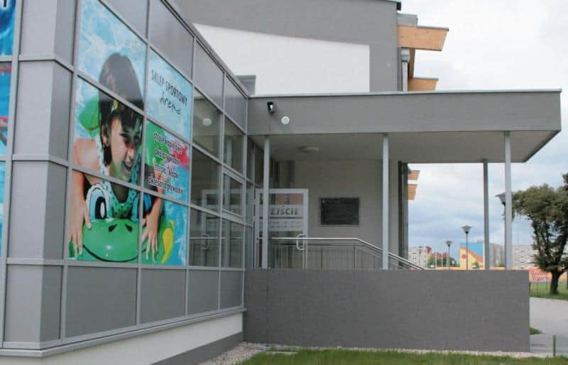 Dekoratives Informationsschild 3 Budynek z dużym plakatem przedstawiającym dziecko na dmuchanym materacu oraz wejściem z napisem "WEJŚCIE".