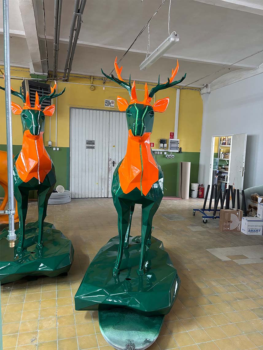 Jägermeister-Hirsche mit LED-Beleuchtung 6 Rzeźby jeleni wykonane z pomarańczowego i zielonego metalu w warsztacie.