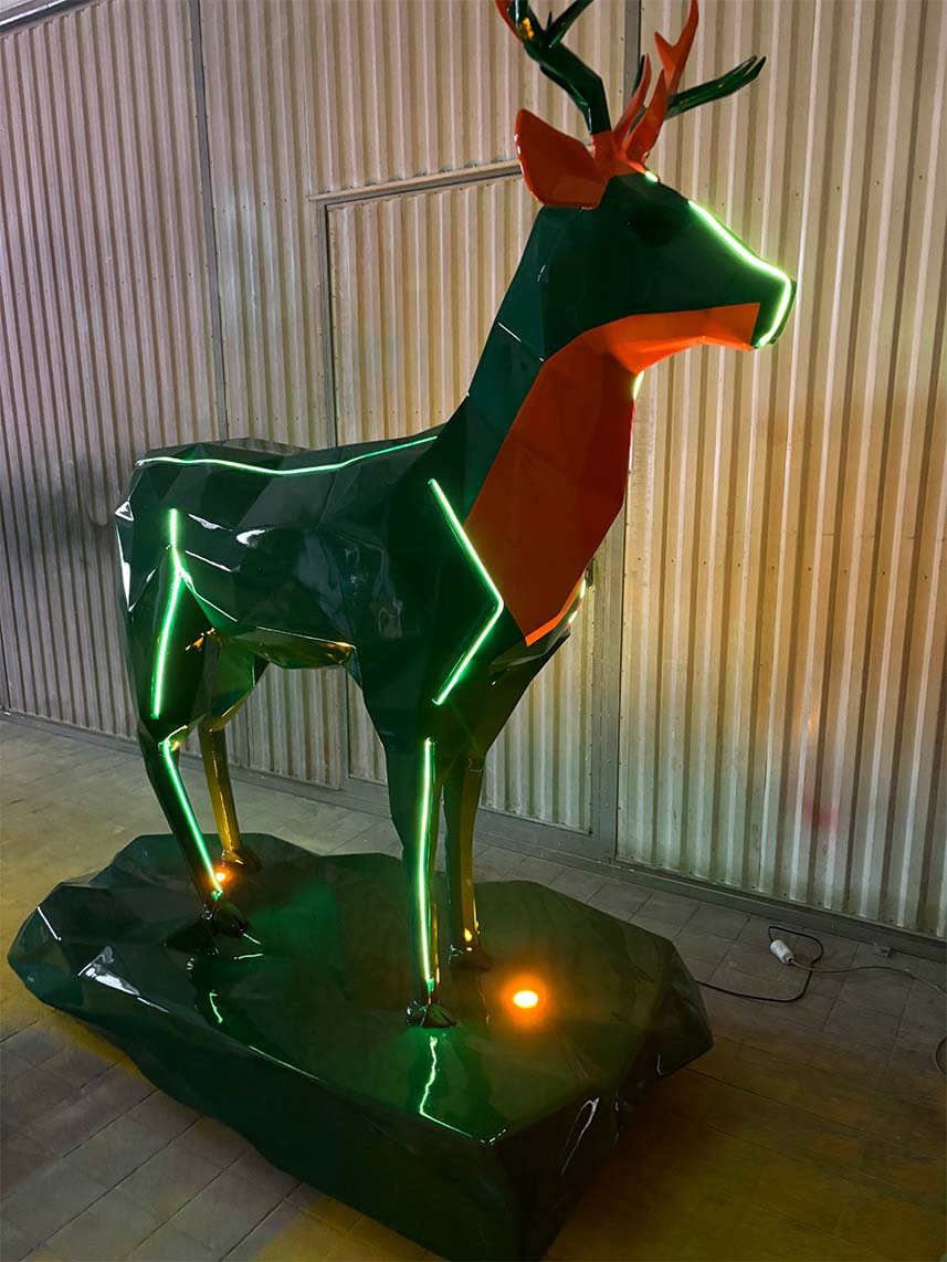 Jägermeister-Hirsche mit LED-Beleuchtung 11 Rzeźba jelenia z neonowymi światłami na stalowym podłożu w hali przemysłowej.