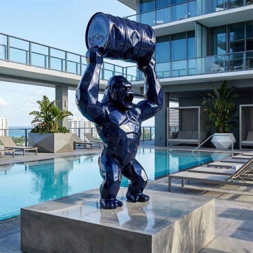Skulptur Gorilla aus Fiberglas, glänzend dunkelblau, geometrischer Stil mit hochgehobenem Fass, Pool- und Hotelterrasse Hintergrund